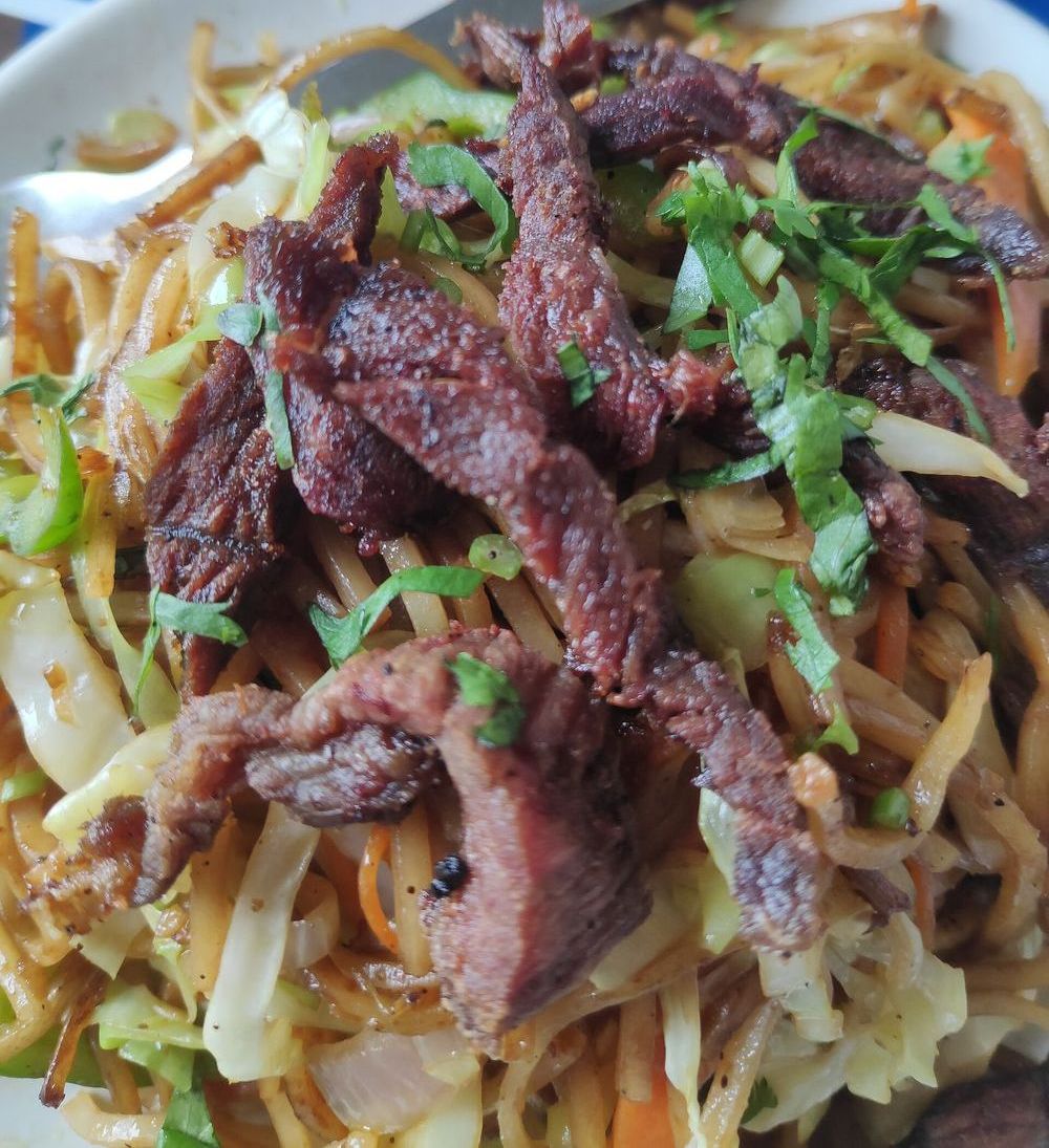 Buff chowmein topped with grilled buff meat and coriander